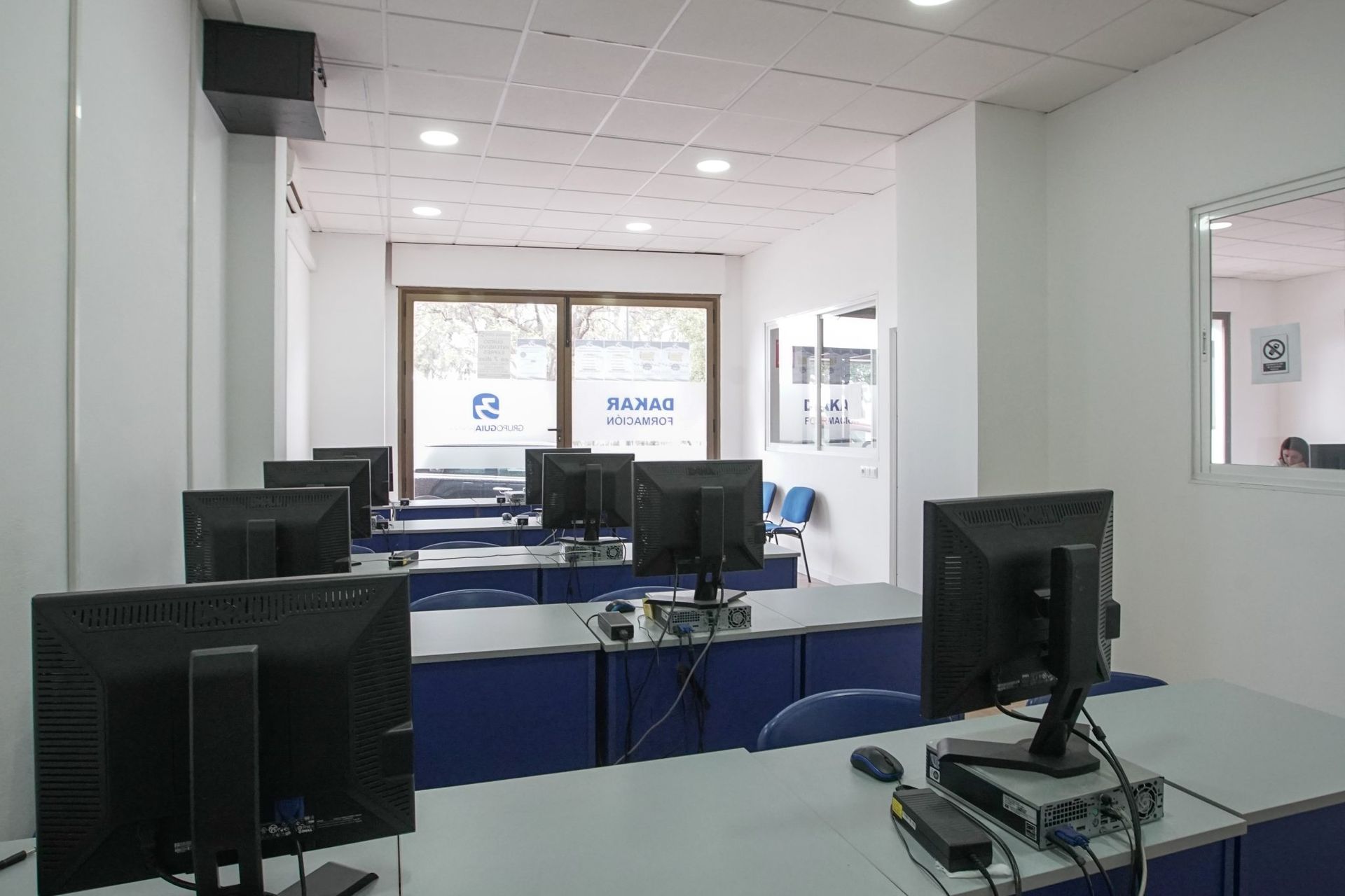 Un aula con muchos monitores de computadora en los escritorios.