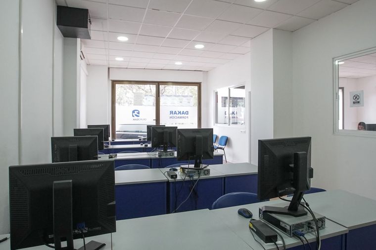 Un aula con muchos monitores de computadora en los escritorios.
