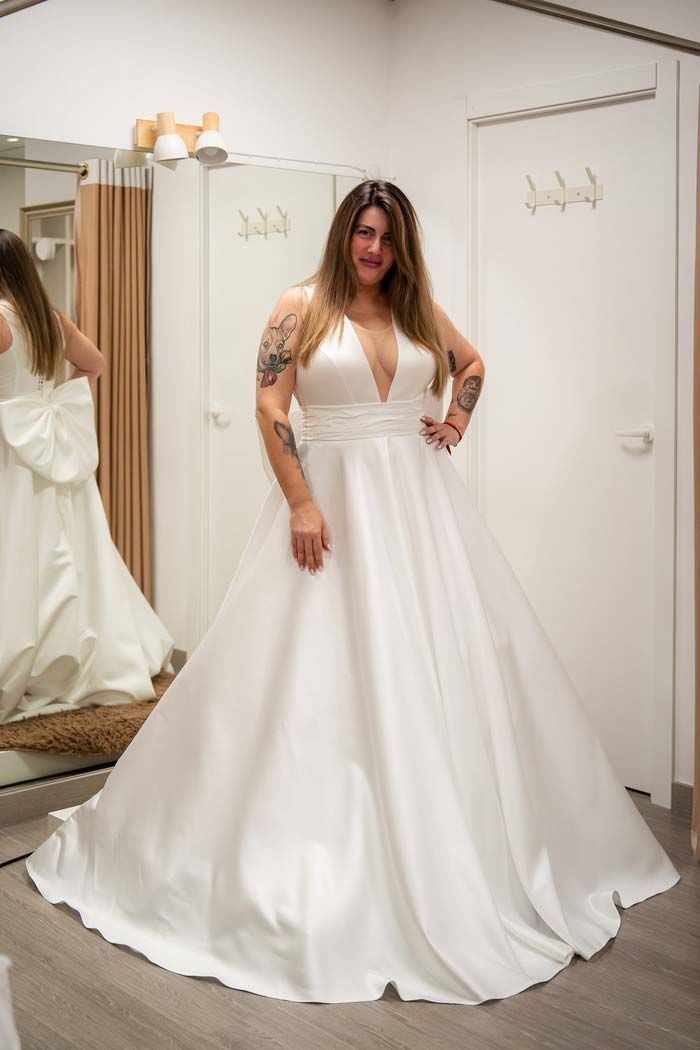 Mujer con un vestido de novia blanco, posando en una tienda de novias.