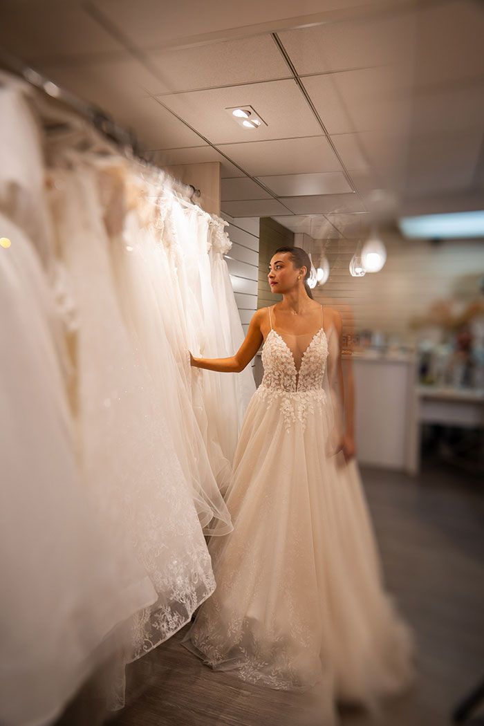 Mujer con un vestido de novia mirando otros vestidos en una tienda de novias.