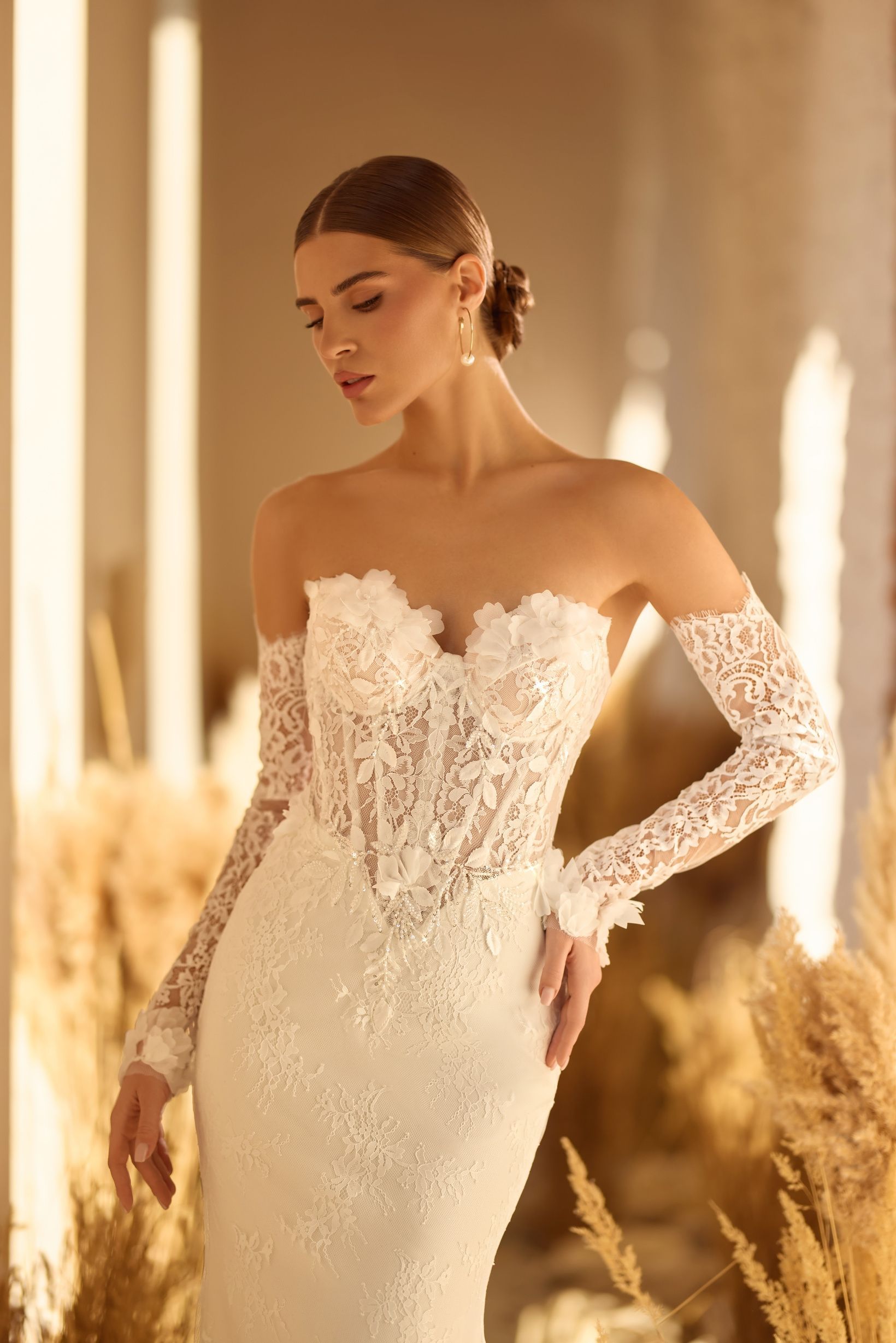 Mujer con un vestido de novia de encaje blanco sin tirantes y guantes largos de encaje, posando.