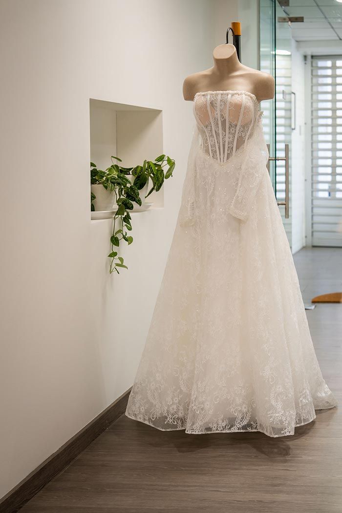 Vestido de novia blanco sobre un maniquí sin cabeza en un pasillo con un nicho para plantas.