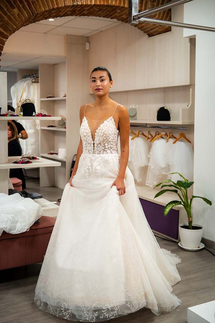 Mujer con un vestido de novia en una tienda de novias, sosteniendo la falda.