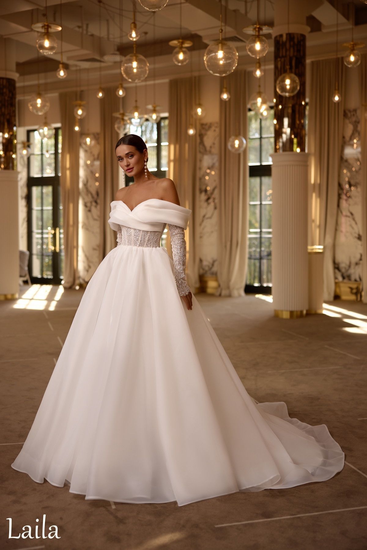 Novia con un vestido de novia blanco con hombros descubiertos en un salón de baile brillante y ornamentado.