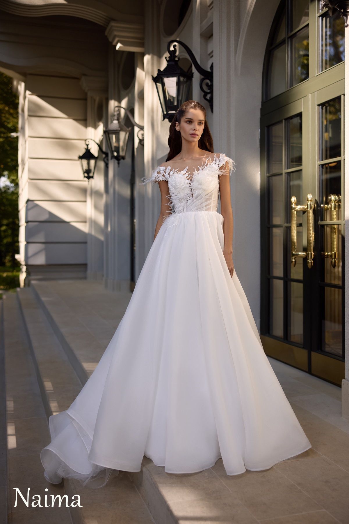 Mujer con vestido de novia blanco de pie fuera del edificio.