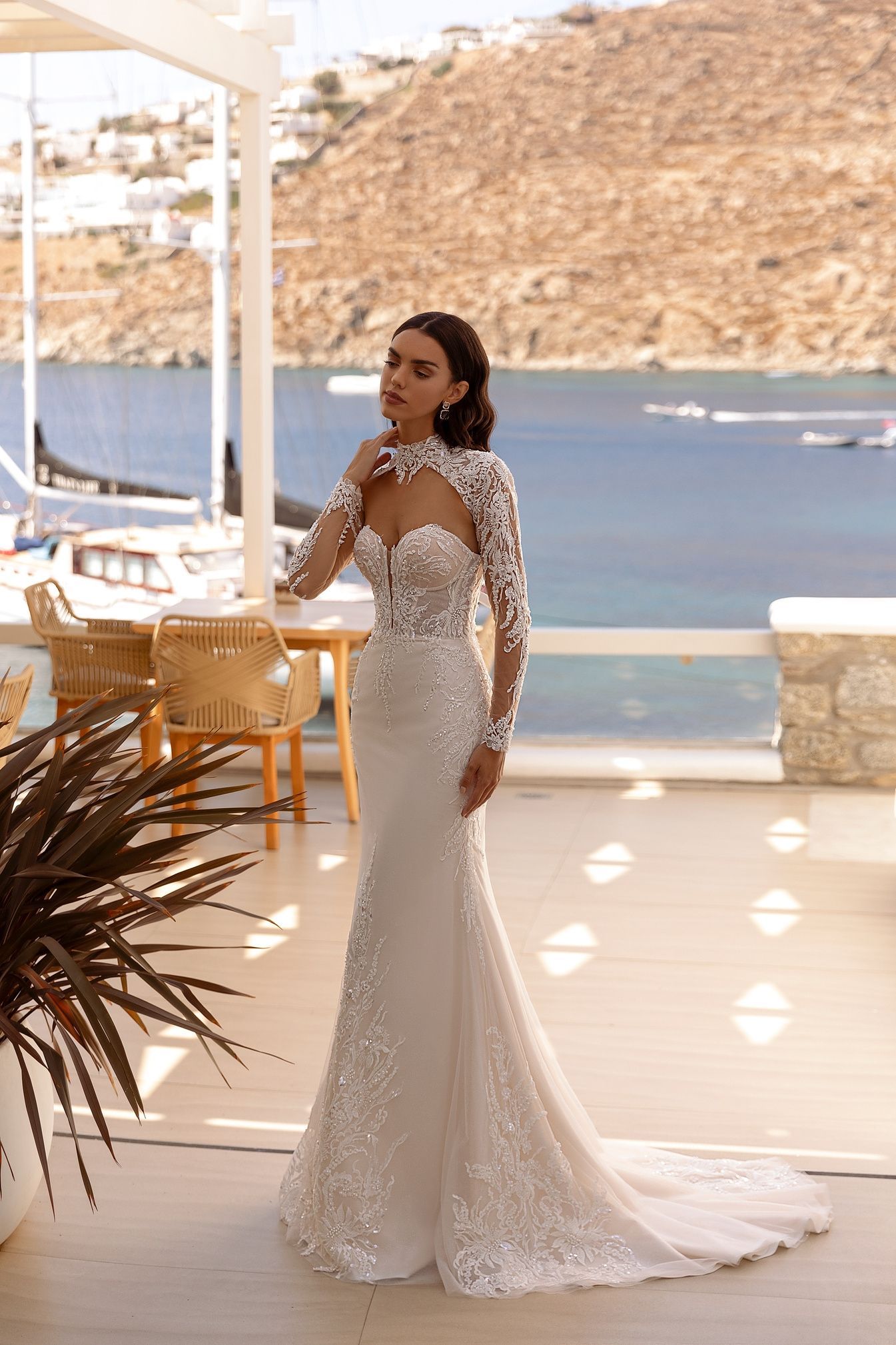 Mujer con un vestido de novia de encaje, posando al aire libre cerca del mar.