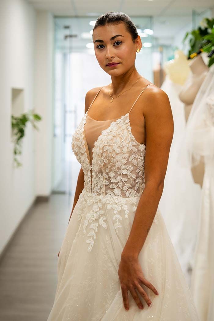 Mujer con un vestido de novia, con escote pronunciado, de pie en una tienda de novias.