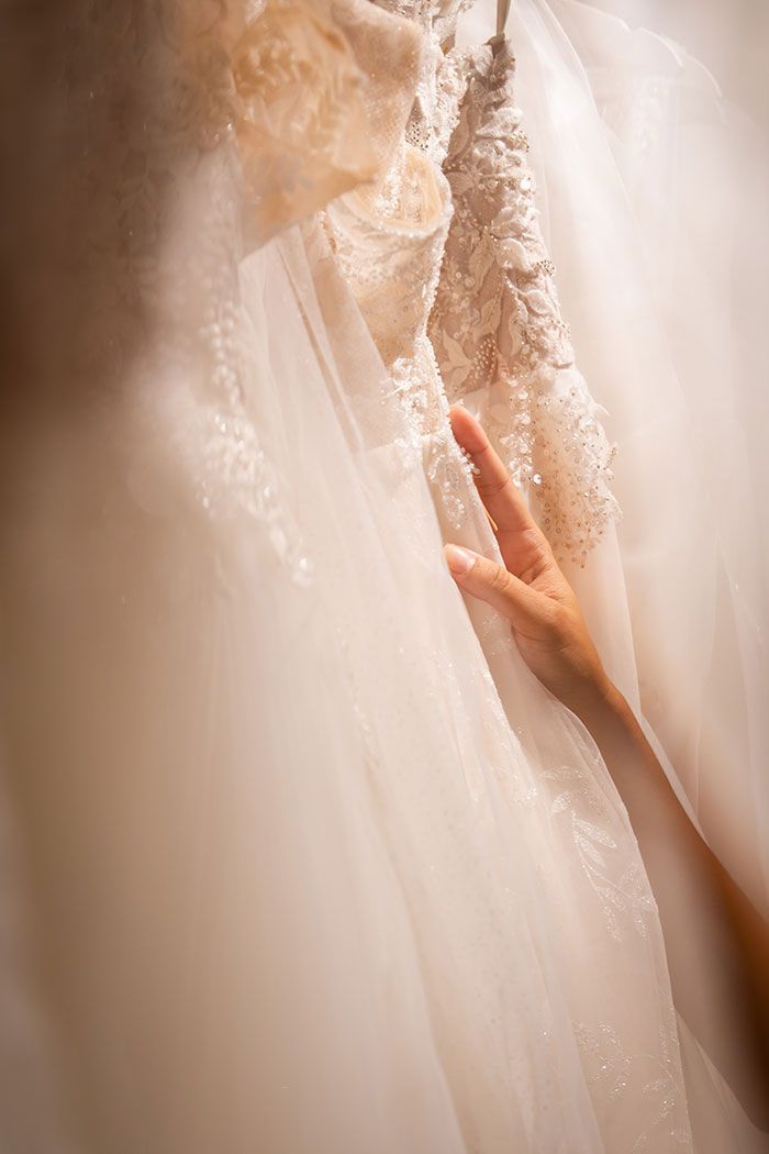 Mano tocando un vestido de novia blanco; vista de cerca.