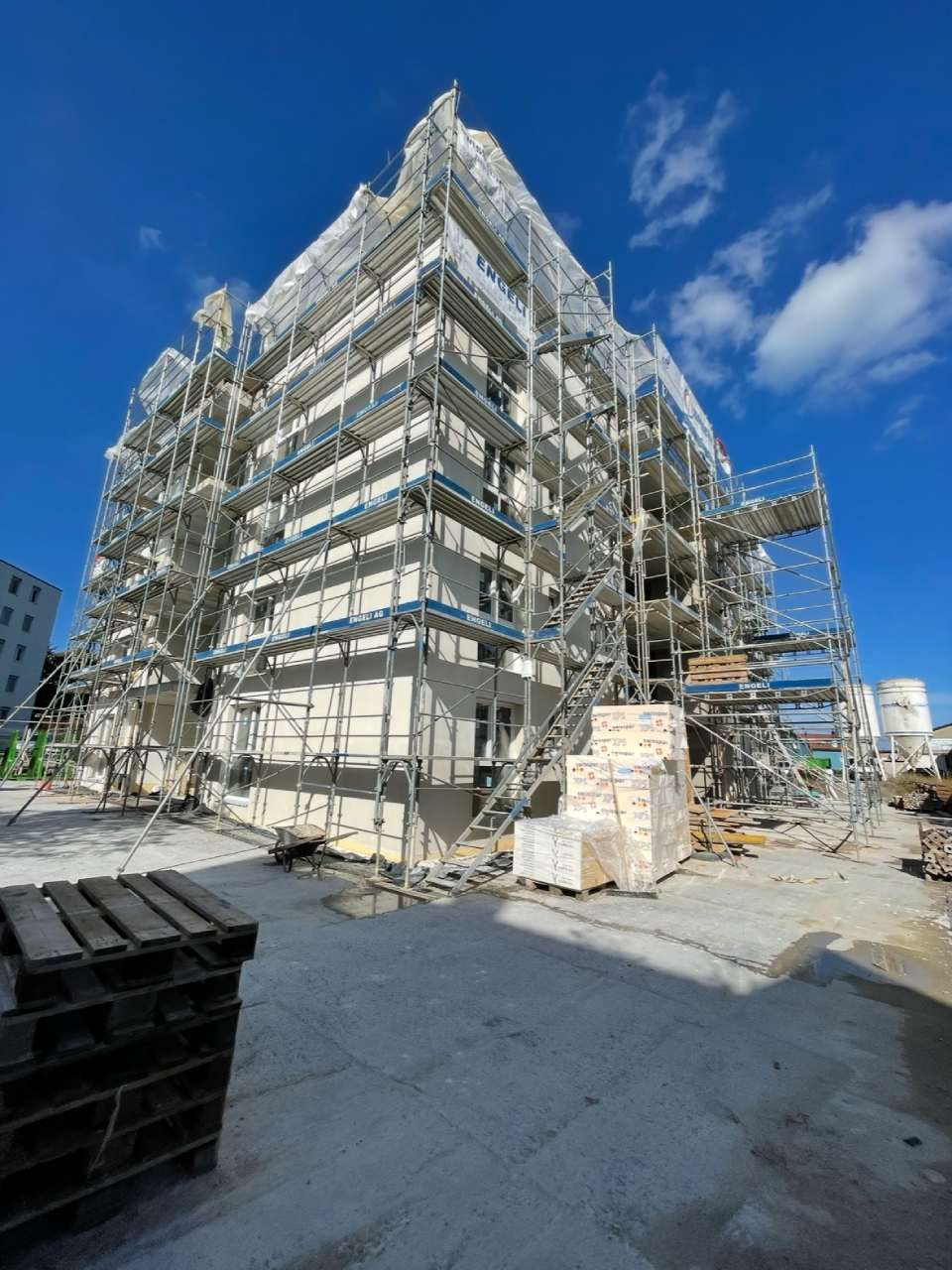 Ein im Bau befindliches Gebäude mit Gerüsten vor blauem Himmel.
