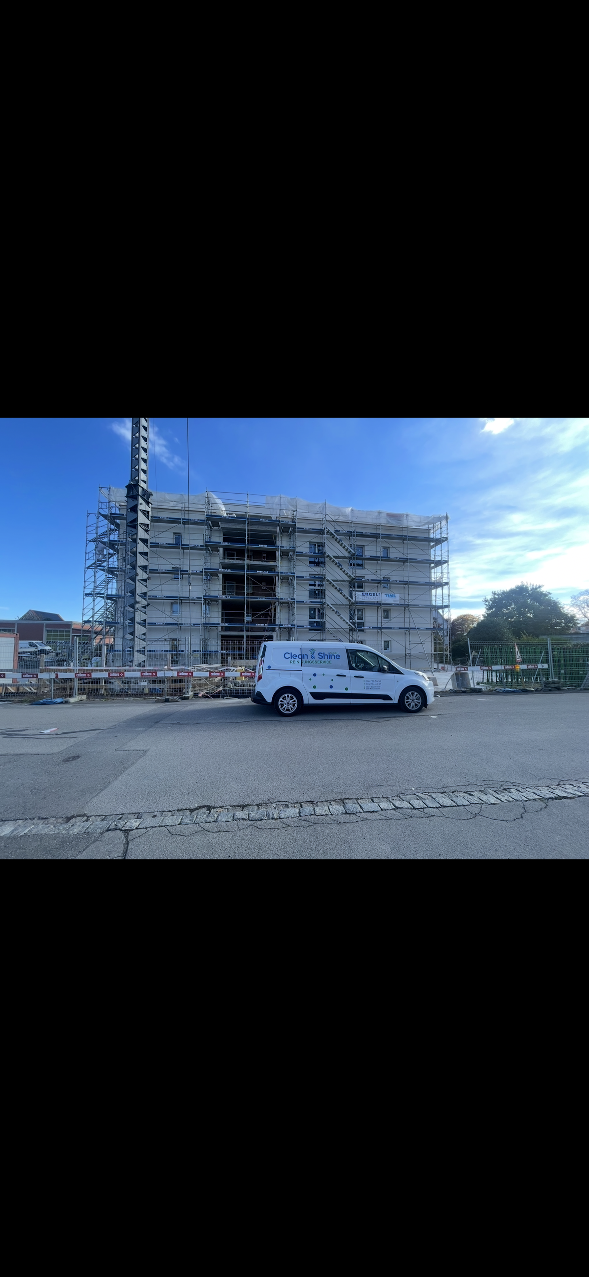 Zwei Personen in grünen Hosen und gelben Handschuhen wischen einen weissen Boden in einem hell erleuchteten Raum.