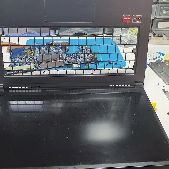 Una computadora portátil negra con un teclado roto está sobre una mesa.