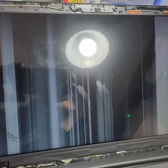 Una computadora portátil con la pantalla rota está sobre una mesa.