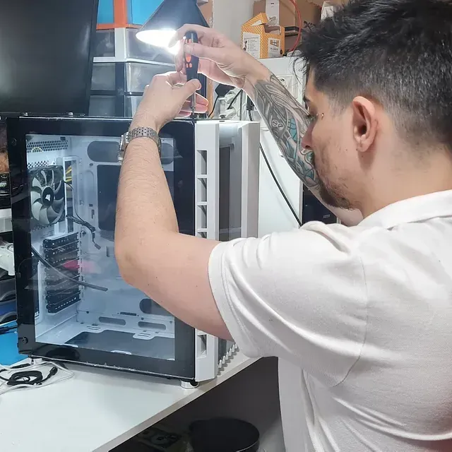 Un hombre con un tatuaje en el brazo está trabajando en una computadora.