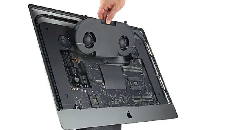 Una persona sostiene un ventilador encima de un monitor de computadora.