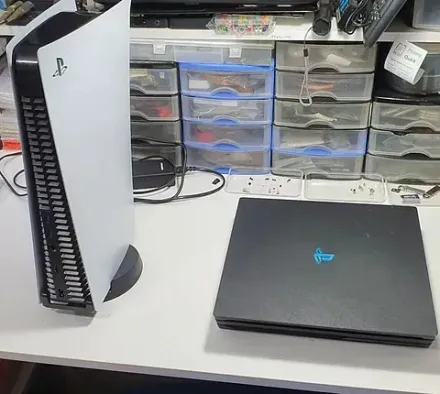 Hay una PlayStation 5 sobre un escritorio al lado de una computadora portátil.