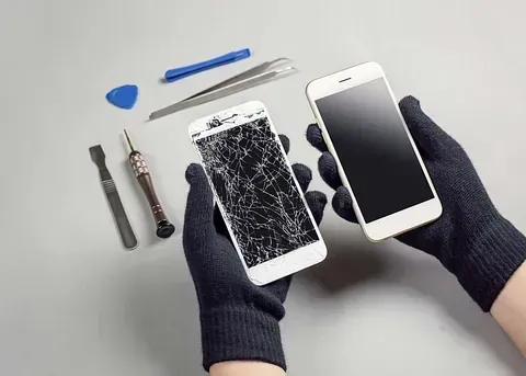 Una persona sostiene un teléfono celular roto en sus manos.
