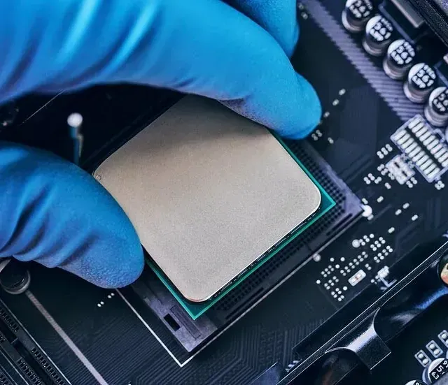 Una persona con guantes azules está instalando una CPU en una placa base.