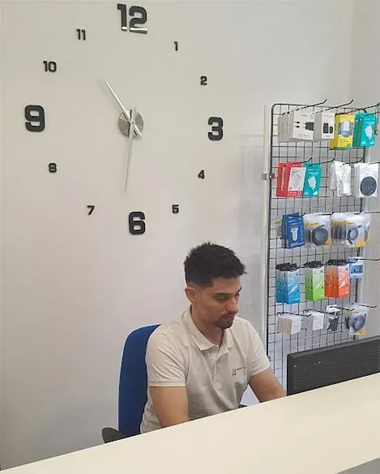 Un hombre se sienta en un escritorio frente a un gran reloj.