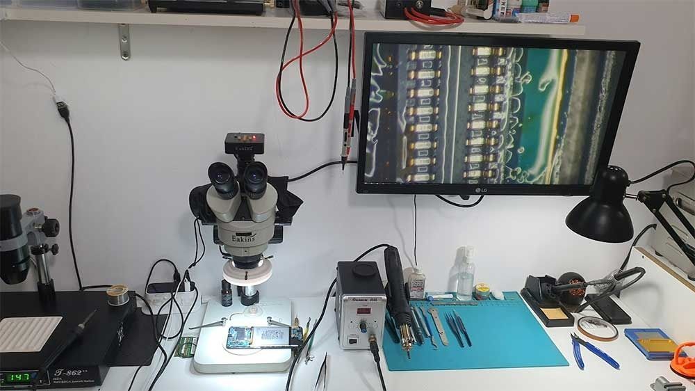 Un escritorio con un microscopio y un monitor encima.