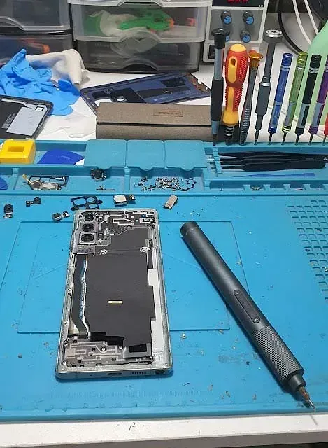 Se está reparando un teléfono celular sobre una alfombra azul