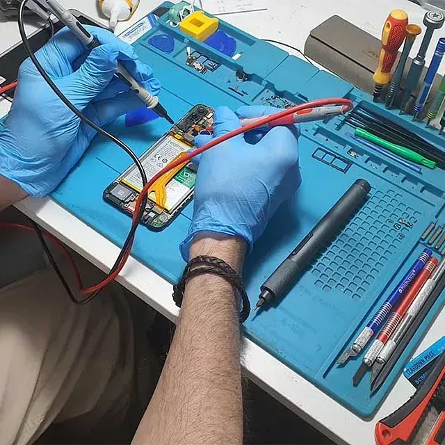 Una persona que lleva guantes azules está trabajando en un teléfono celular.