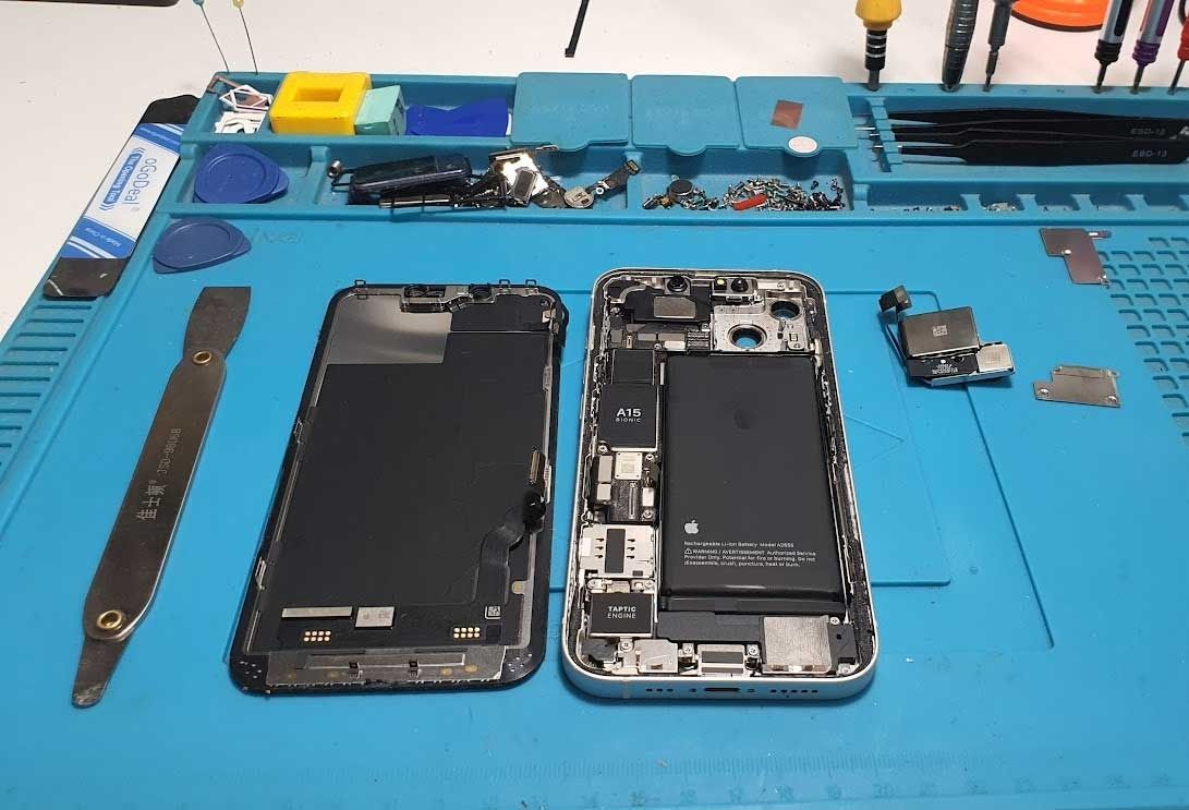 Se está reparando un teléfono celular sobre una alfombra azul.