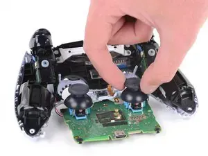 Una persona sostiene dos joysticks encima de un controlador de videojuego.