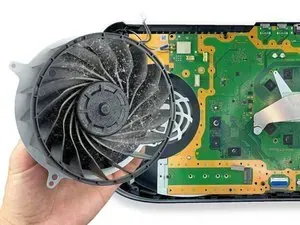 Una persona sostiene un ventilador sucio delante de una placa base.