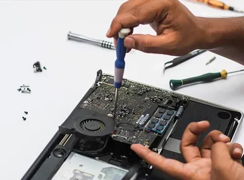 Una persona está arreglando una computadora portátil con un destornillador.