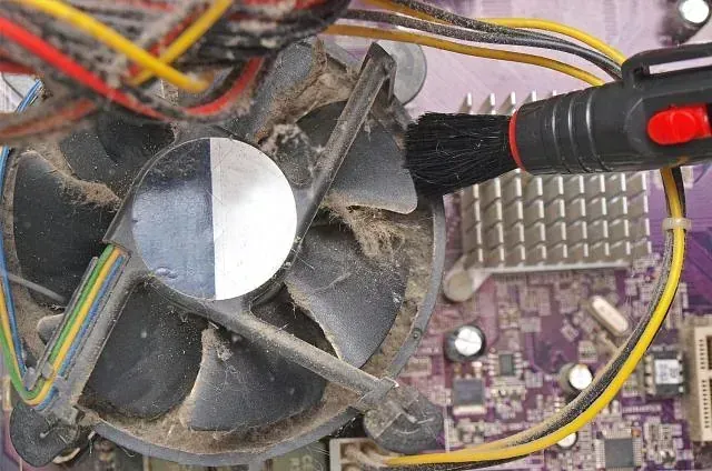 Se está limpiando un ventilador de computadora sucio con un cepillo
