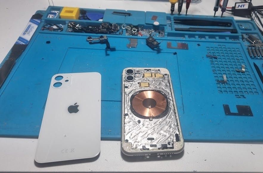 Un iPhone blanco se está reparando sobre una alfombra azul.