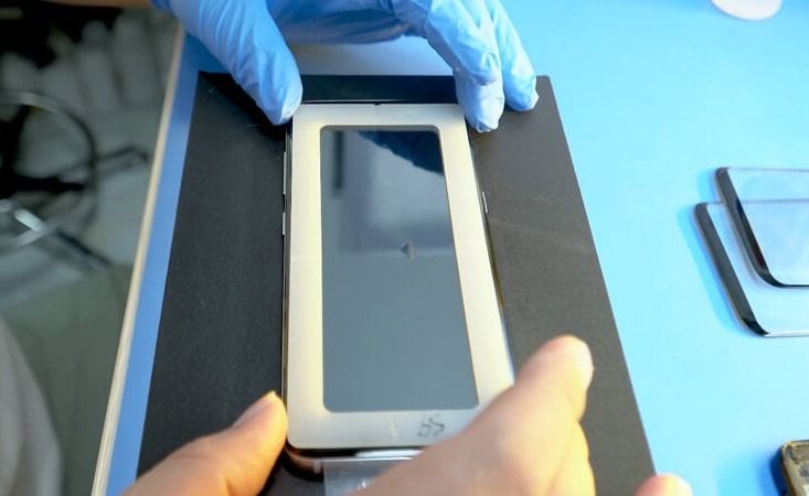 Una persona que lleva guantes azules sostiene un teléfono celular.