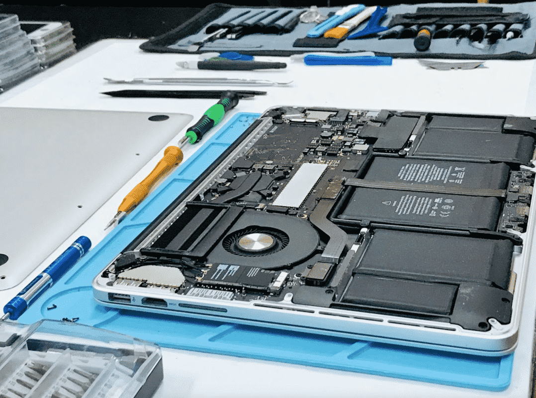 Se está reparando una computadora portátil en una mesa con herramientas.