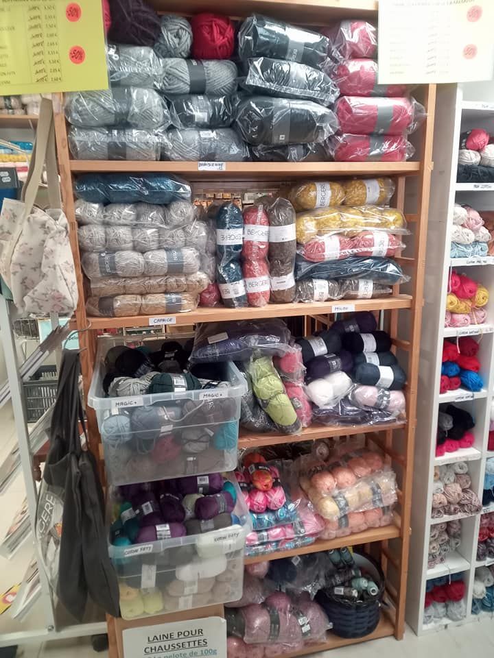 Étagère remplie de différentes pelotes de laine dans des sacs plastiques transparents.