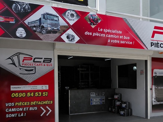 Devanture de magasin de pièces automobiles avec enseigne rouge et entrée de garage ouverte