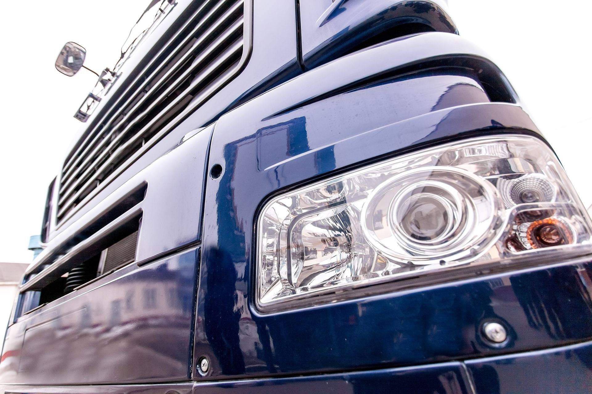 Gros plan sur la calandre et le phare avant d'un camion bleu par une journée ensoleillée
