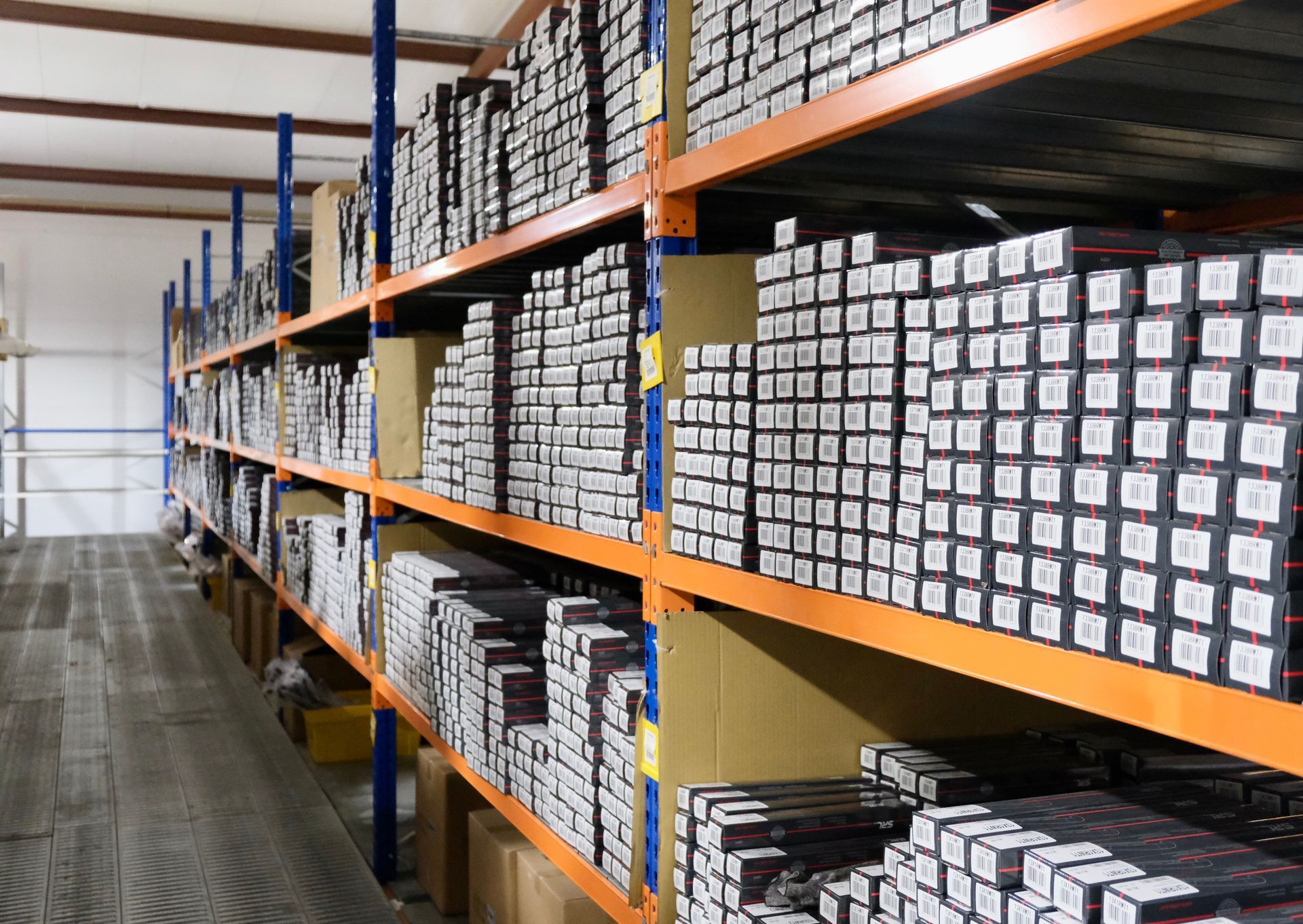 Allée d'entrepôt avec de hautes étagères remplies de cartons et de marchandises emballées