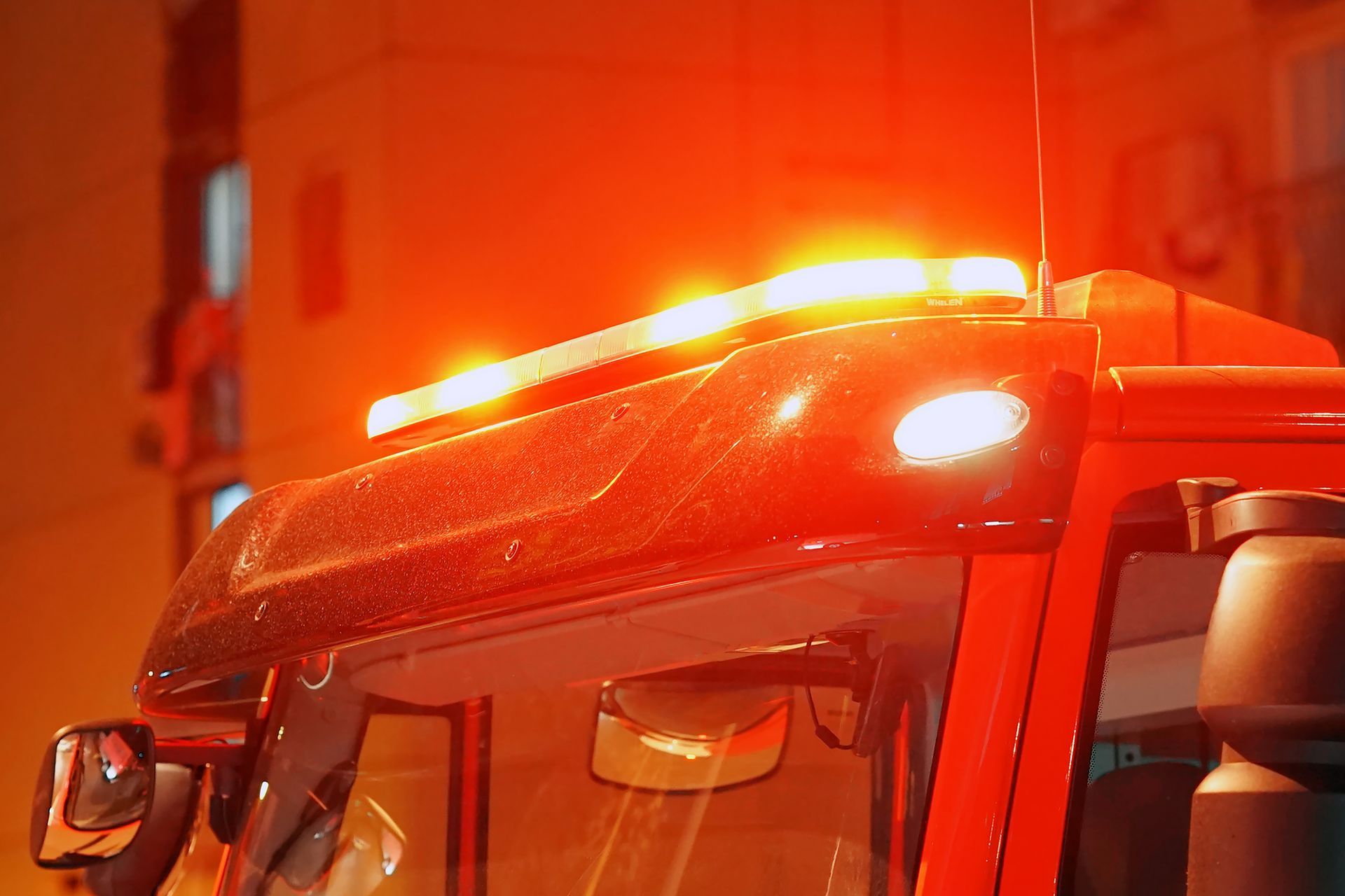Gros plan d'un véhicule d'urgence rouge avec gyrophares clignotants sur le toit, de nuit.