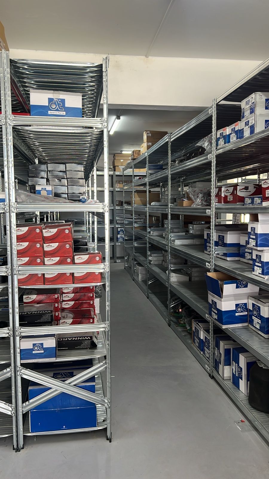 Allée d'entrepôt avec de hautes étagères remplies de cartons et de marchandises emballées