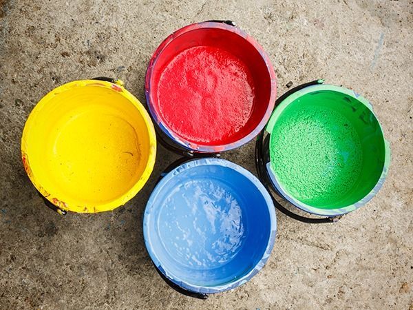 Hay cuatro cubos de pintura de diferentes colores en el suelo.