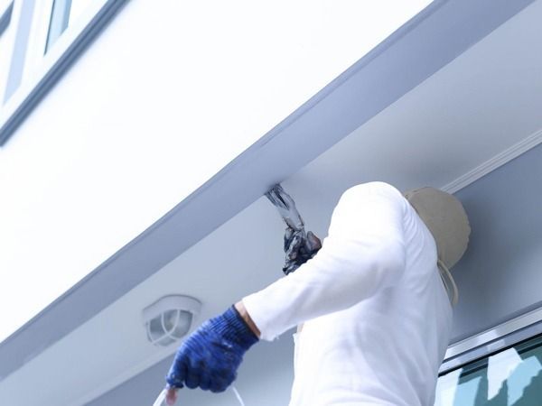 Un hombre está pintando el techo de un edificio.