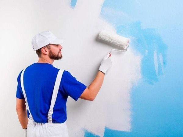Un hombre está pintando una pared con un rodillo de pintura.