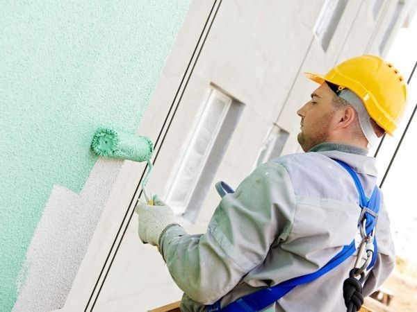 Un hombre que lleva un casco está pintando una pared con un rodillo.