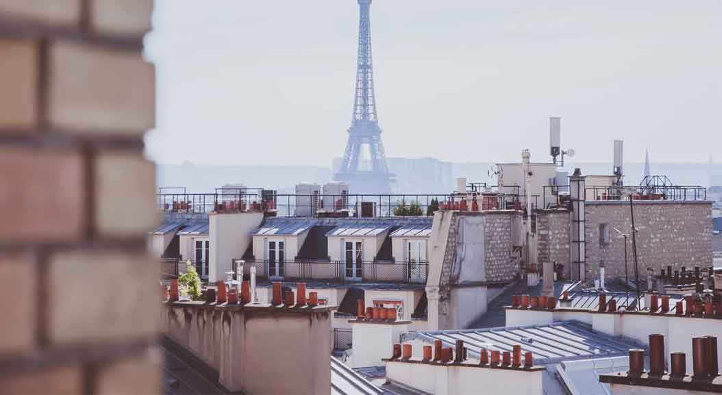 Toits de Paris avec la tour Eiffel en arrière-plan, par temps nuageux.