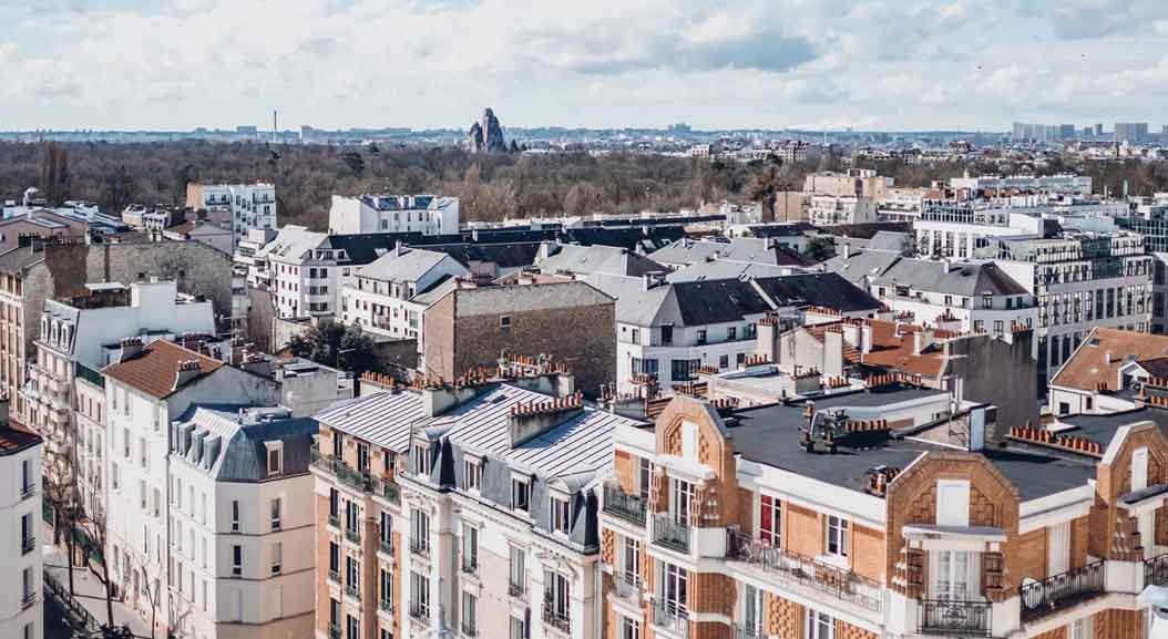 Paysage urbain avec des bâtiments variés sous un ciel nuageux.