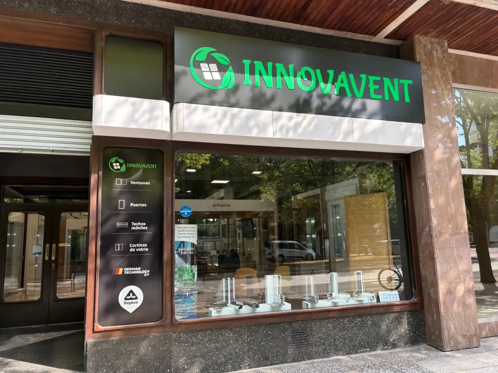 Fachada de Innovavent con letrero verde y gran escaparate bajo una pasarela cubierta.
