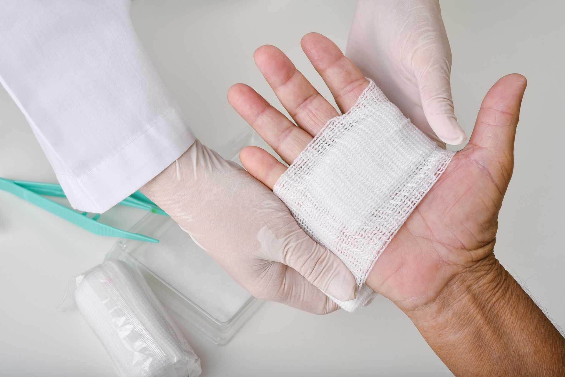 Des mains avec des gants médicaux blancs enroulent un bandage autour d'une main blessée