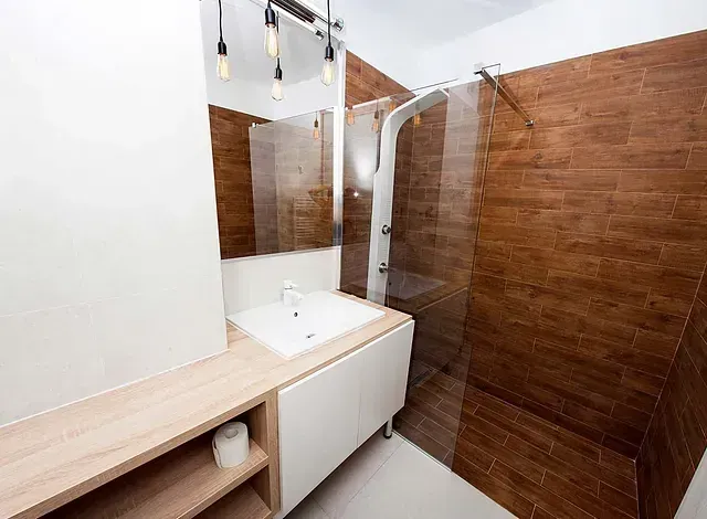 Un baño con lavabo, espejo y ducha.