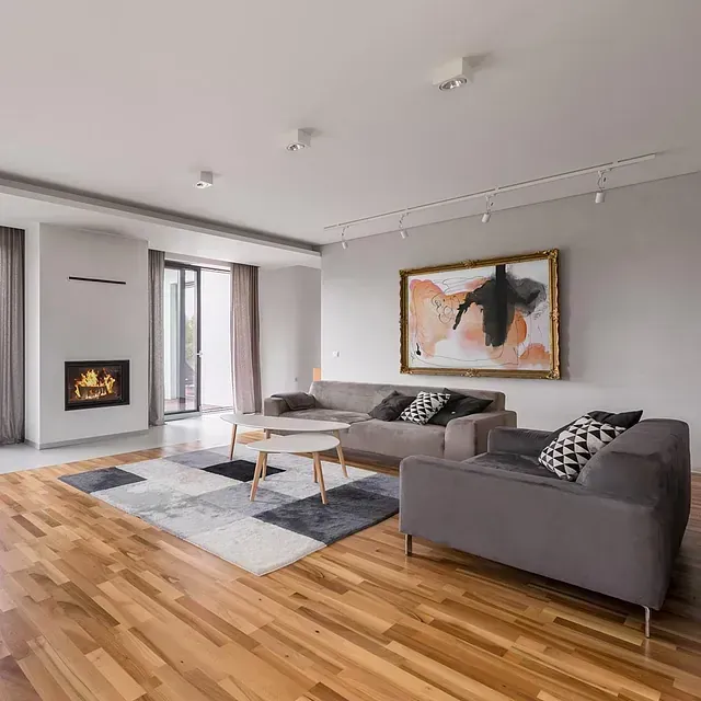 Una sala de estar con pisos de madera, dos sofás, una mesa de café y una chimenea.