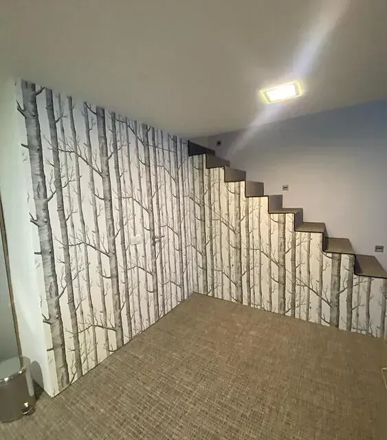 Una habitación con escaleras y una pared con árboles.